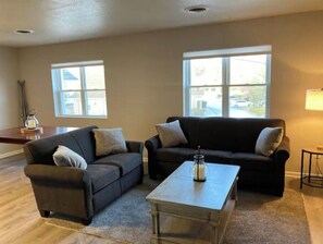 Relax in this inviting living room with two sofas, a glass table, and a large window.
