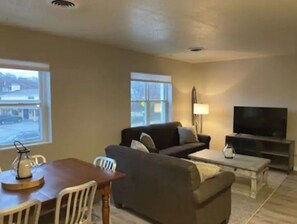 Relax in this stylish living room with a large window, sofa, coffee table, flat-screen TV, dining table, and comfortable seating.