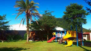A playground with a slide, climbing structures, and a palm tree. - Sun Moon Cat (Yuchi)