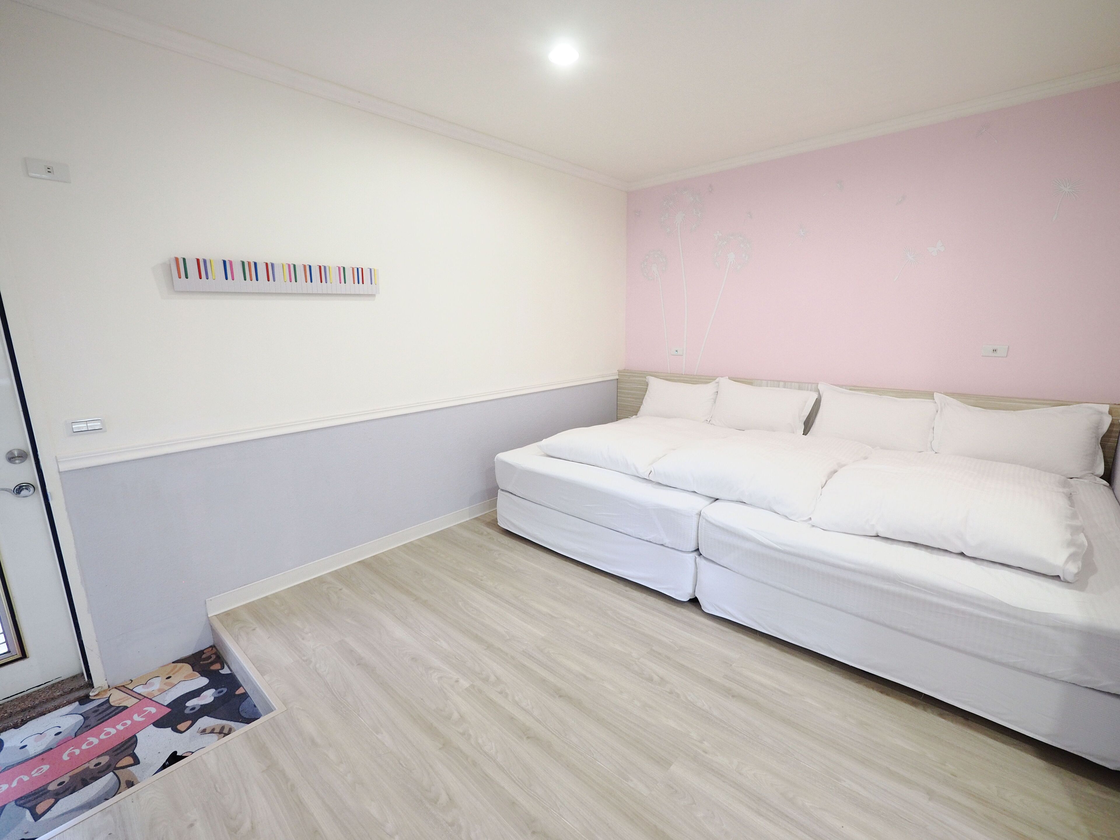 A bedroom with a bed, a wall-mounted light, and a door.