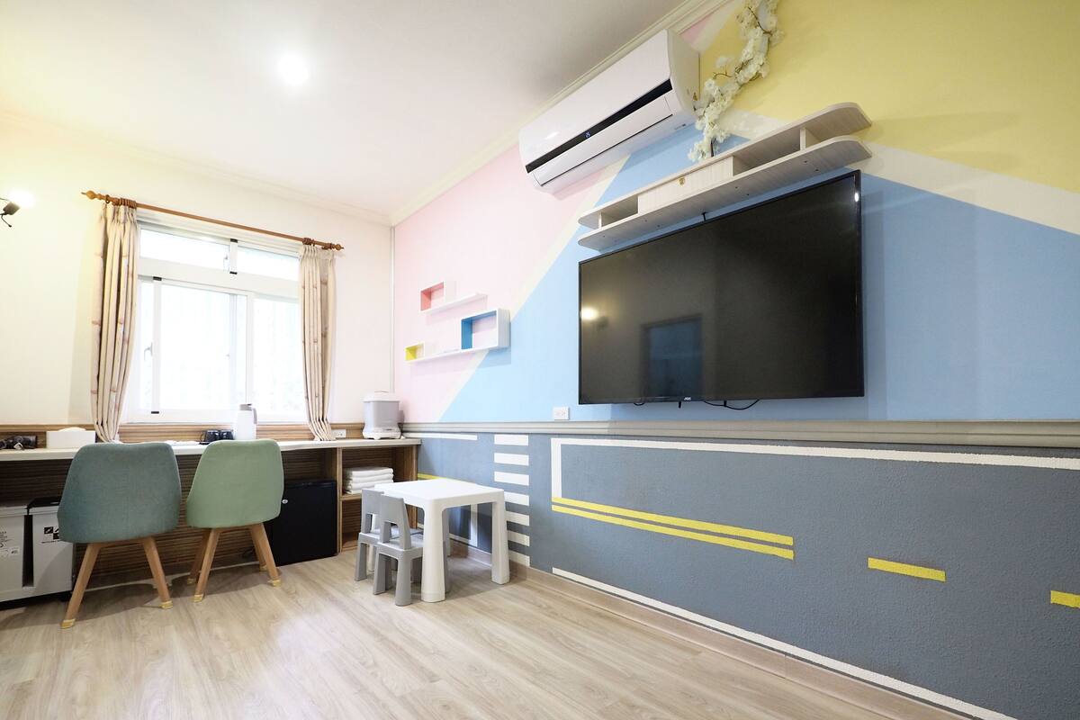 A compact kitchen with a TV, wooden cabinets, and a window with curtains.