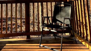 A wooden deck with a metal chair, surrounded by trees and a clear sky. - Modern, family-friendly, nature packed getaway (Berkeley Springs)