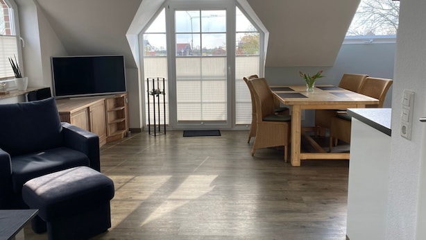 Una habitación moderna estilo loft, con zona de comedor, rincón de estar y televisor.