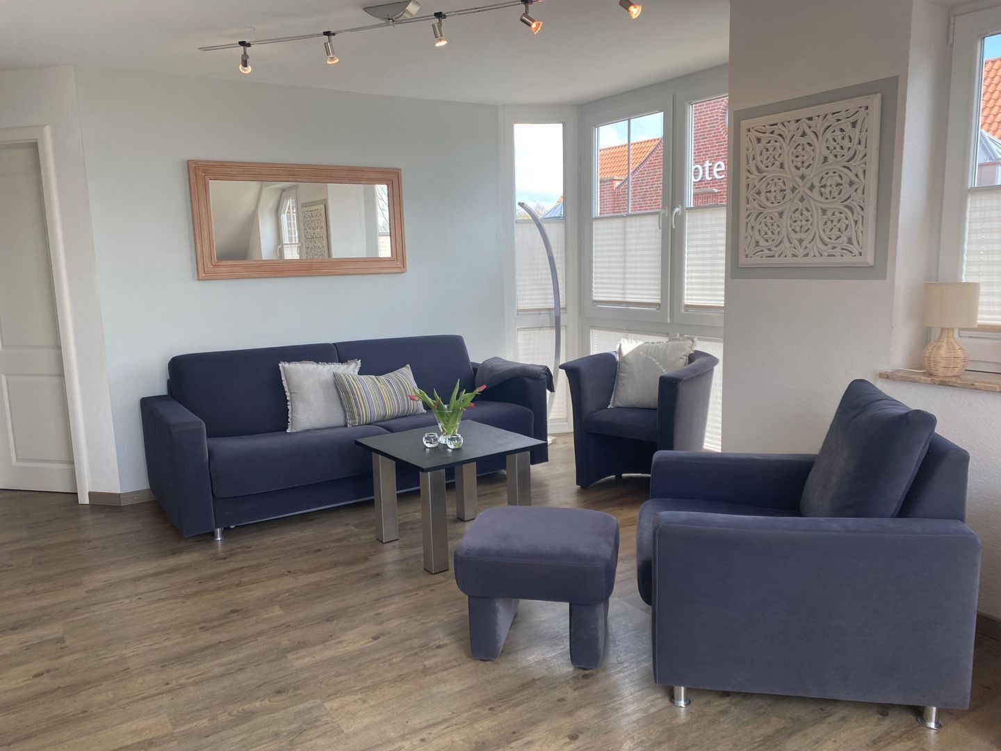 Una sala de estar moderna con un sofá azul oscuro, un sillón a juego y una mesita con un jarrón de flores.