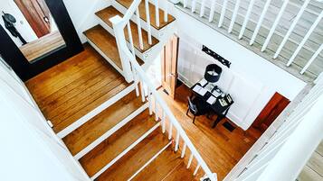 Un escalier en bois à plusieurs niveaux avec des rampes blanches, un bureau avec une chaise et une fenêtre en arrière-plan.