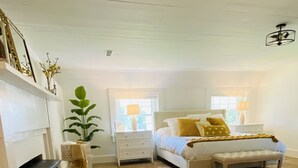A bedroom with a bed, bedside tables, a fireplace, and a large window. - The Hopestead Bed & Breakfast (Fayetteville)