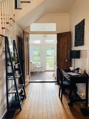A room with a wooden floor, a desk with a lamp, a chair, and a bookshelf. There is a door leading to a balcony with a view of the outdoors. - The Hopestead Bed & Breakfast (Fayetteville)