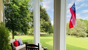 A covered porch with a bench, a chair, and a flag. - The Hopestead Bed & Breakfast (Fayetteville)