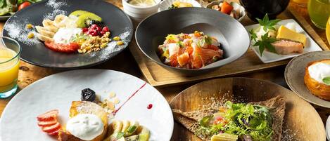 A variety of breakfast dishes including pancakes, smoked salmon, and a salad on a wooden table.