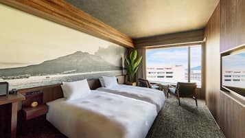 A hotel room with a large bed, a desk with a clock, a chair, a large window with a view of a mountain and water, and a plant.
