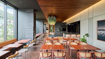 Un interior de restaurante moderno con mesas y sillas de madera, ventanas amplias y una exhibición central de plantas.
