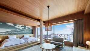 Moderni hotellihuone, jossa on suuri sänky, sohva, pyöreä pöytä ja näkymä kaupunkiin.