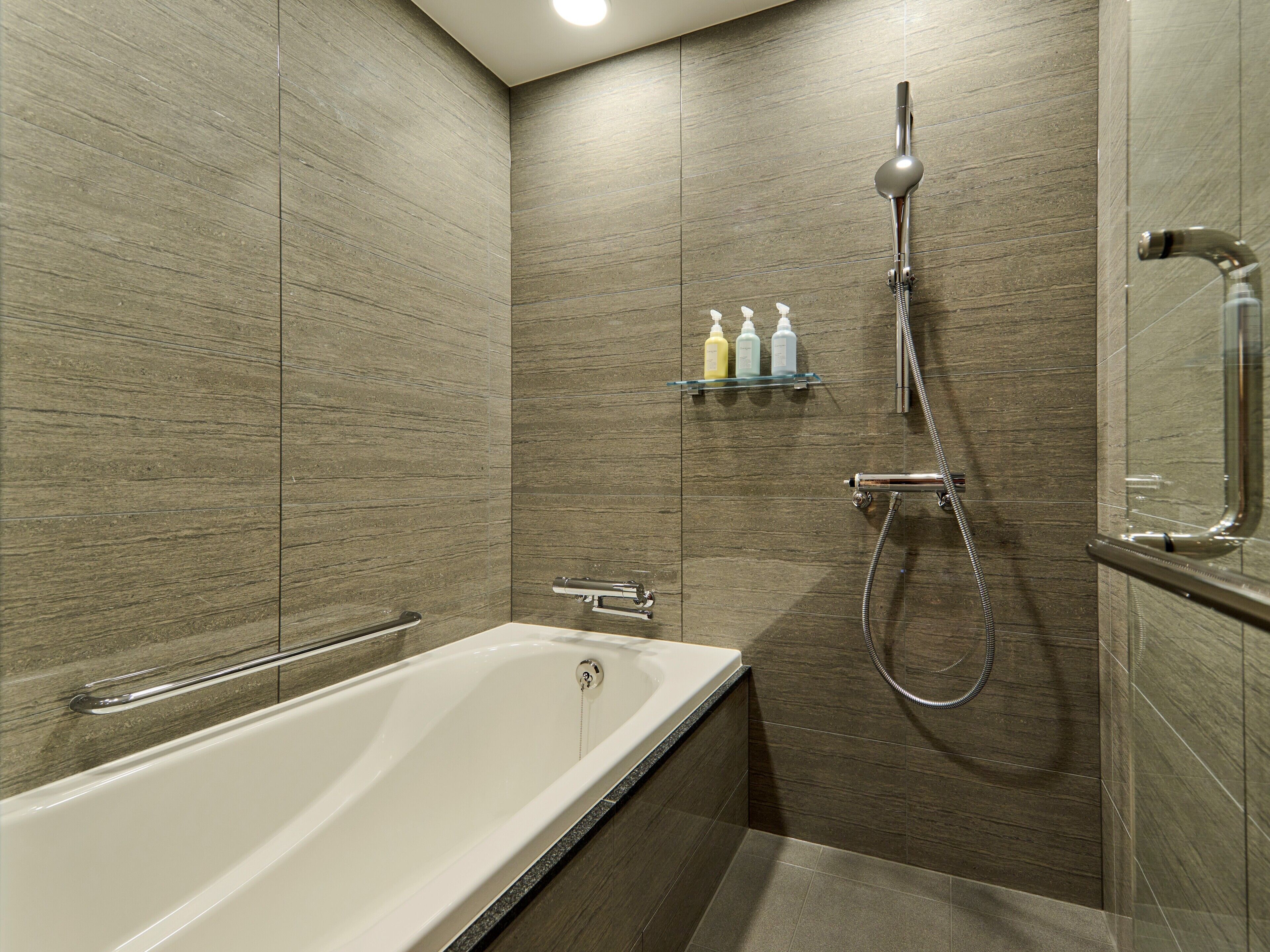 Un baño moderno con bañera, ducha y un estante con artículos de aseo.