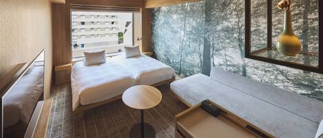 A modern hotel room with two beds, a small round table, and a large window offering a view of trees.