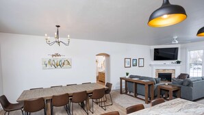 Una sala de estar moderna con comedor, chimenea y televisor montado en la pared.