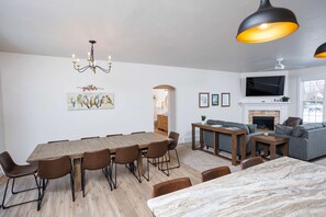 A modern living room with a dining area, a fireplace, and a television mounted on the wall. - Downtown Sister Bay: 2022 New Construction home (Sister Bay)