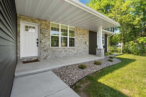 A residential house with a stone facade, a white door, and a large window. - Downtown Sister Bay: 2022 New Construction home (Sister Bay)