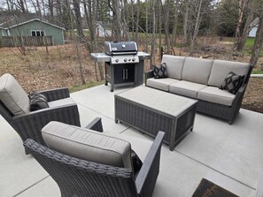 Eine Terrasse im Freien mit Grill, Korbmöbeln und einer Sitzecke.