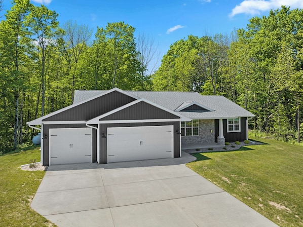 A two-story house with a garage, a covered porch, and a well-maintained lawn.