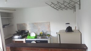 Eine kleine Küche mit Gaskochfeld, Spüle und kleinem Kühlschrank.