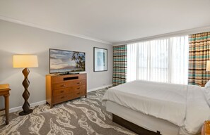 Une chambre d’hôtel avec un lit, une commode en bois, une lampe et une fenêtre avec des rideaux.