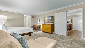 A hotel room with a bed, a desk, a dresser, and a painting on the wall.