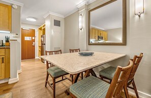 A dining area with a marble table, wooden chairs, and a large mirror above the table. - Maui Resort Rentals: Marriott's Maui Ocean Club 1BR Mountain/Garden View Villa (Lahaina)
