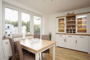 Una cocina moderna con armarios blancos, encimera de madera y comedor con mesa y sillas.