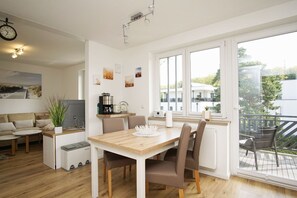 Una cocina moderna con comedor, suelo de madera y ventanas amplias con vistas al exterior.
