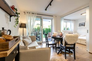 A cozy living room with a sofa, a dining table with chairs, a coffee table, and a window with curtains. - Casa Fiammetta near Bruneck (Brunico)