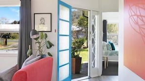 Porta corredissa oberta que dona a un balcó amb vista a un jardí i un edifici.
