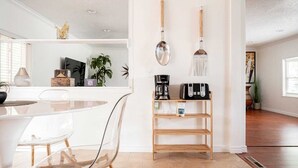 Une cuisine moderne avec un coin repas, comprenant un plan de travail blanc, une machine à café et un grille-pain.