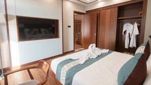 A hotel room with a bed, a wooden chair, a wardrobe, and a TV mounted on the wall. - VIENTIANMEKONGHOTEL (Vientiane)