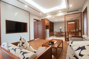 A modern living room with a sofa, a coffee table, and a TV mounted on the wall. - VIENTIANMEKONGHOTEL (Vientiane)