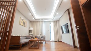 A modern living room with a sofa, coffee table, and a TV mounted on the wall. - VIENTIANMEKONGHOTEL (Vientiane)