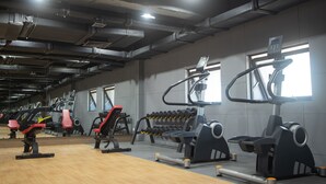 A gym with exercise equipment, mirrors, and windows. - VIENTIANMEKONGHOTEL (Vientiane)