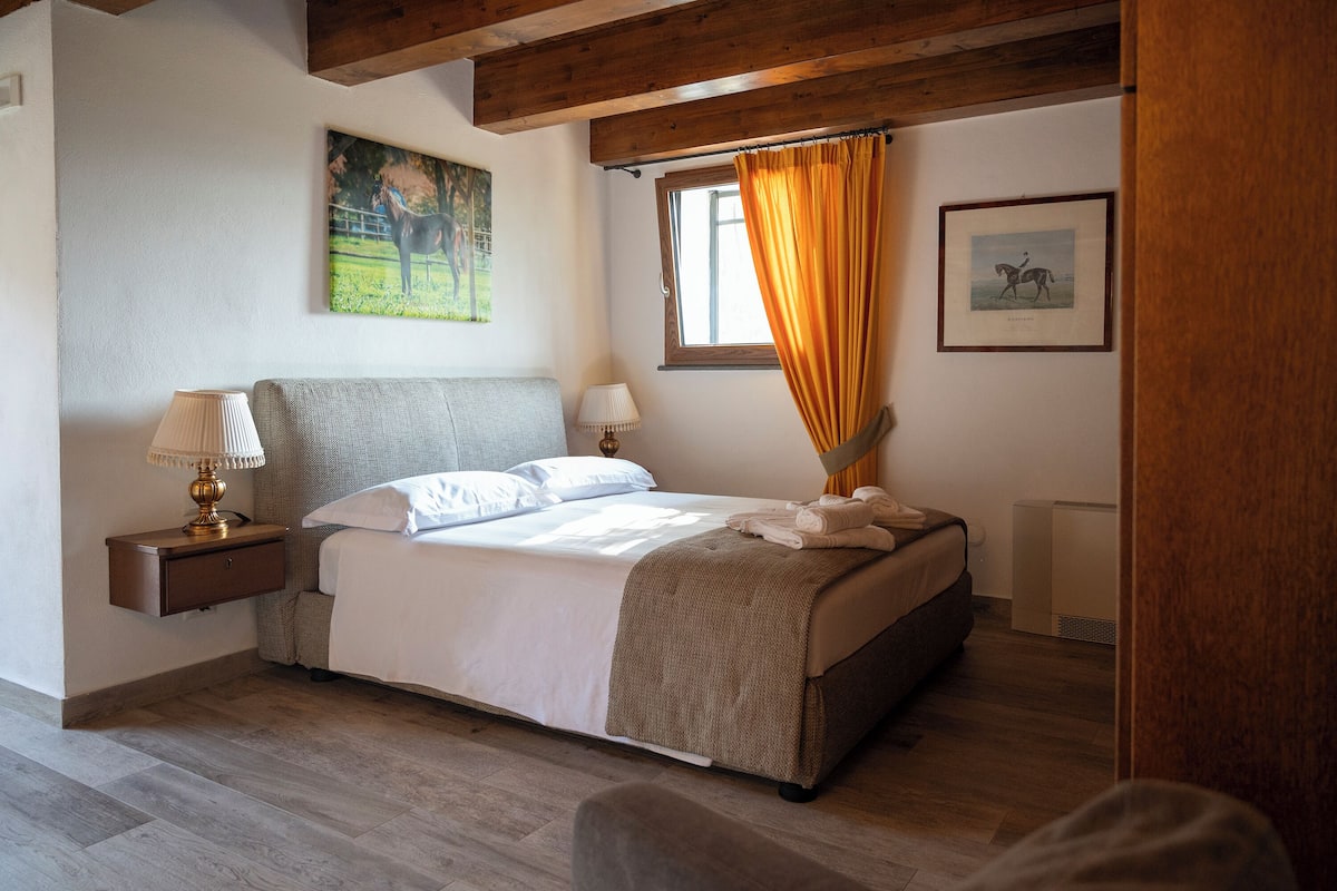 Une chambre à coucher avec un lit, une table de chevet, une lampe et deux tableaux encadrés accrochés au mur.