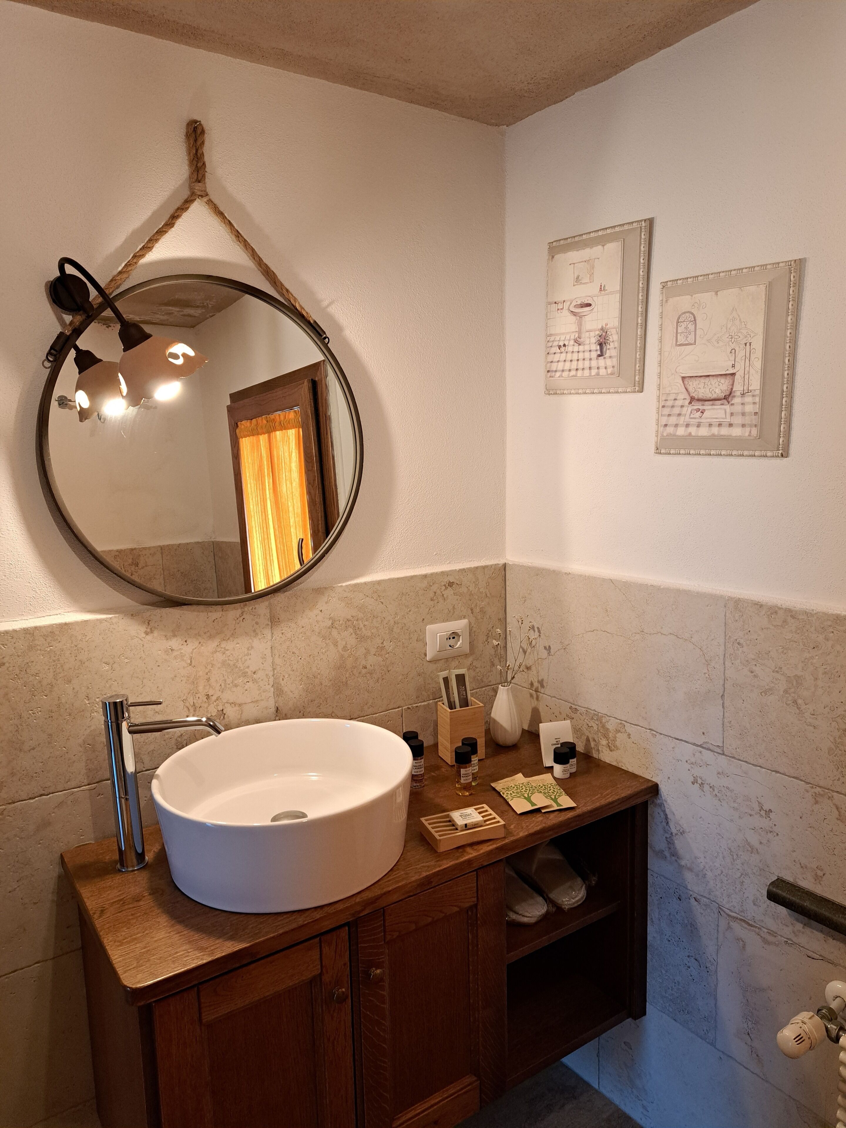 A bathroom with a round mirror, a white sink, wooden cabinets, and a towel rack.