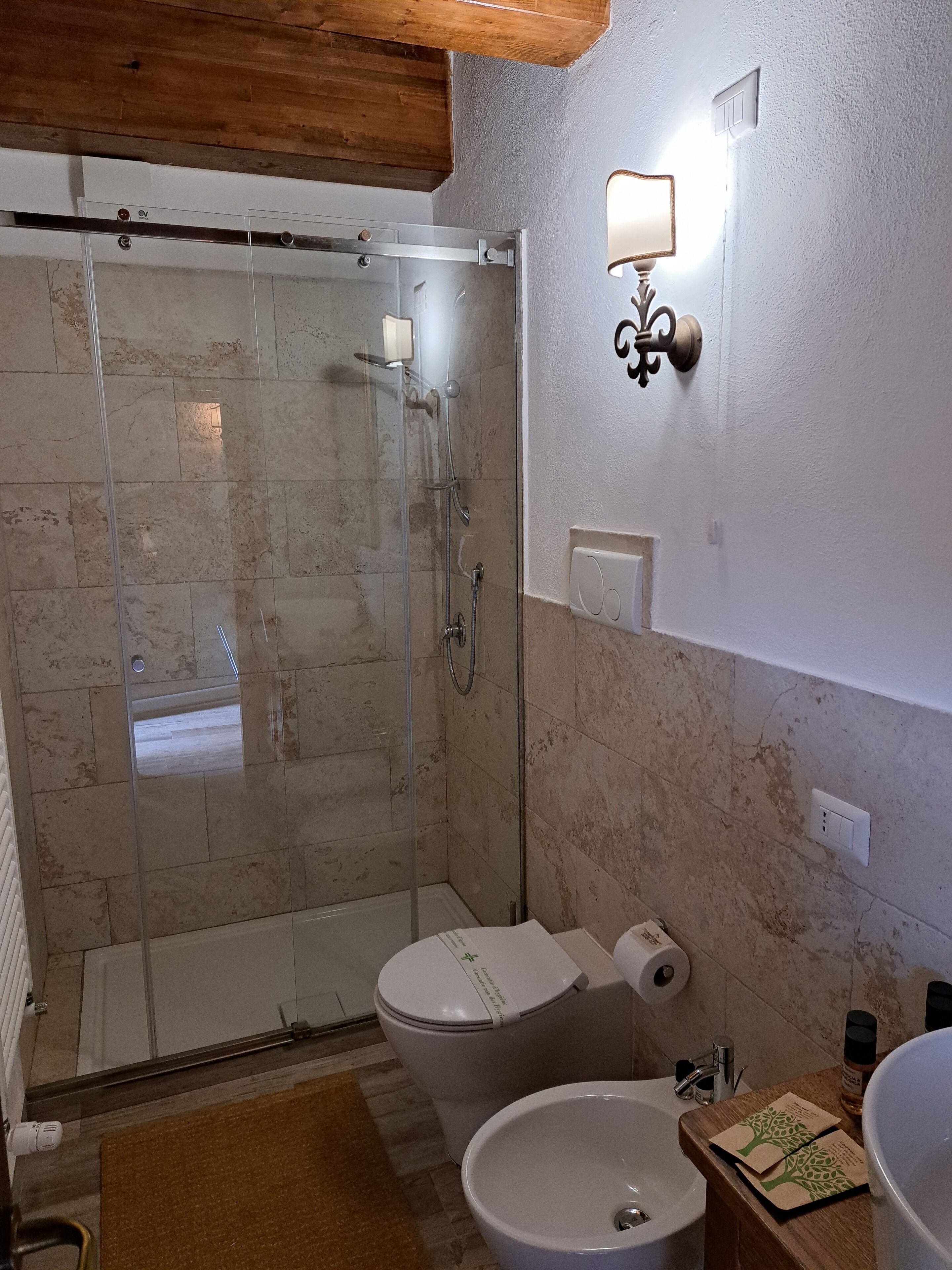 A bathroom with a glass-enclosed shower, a toilet, and a sink.