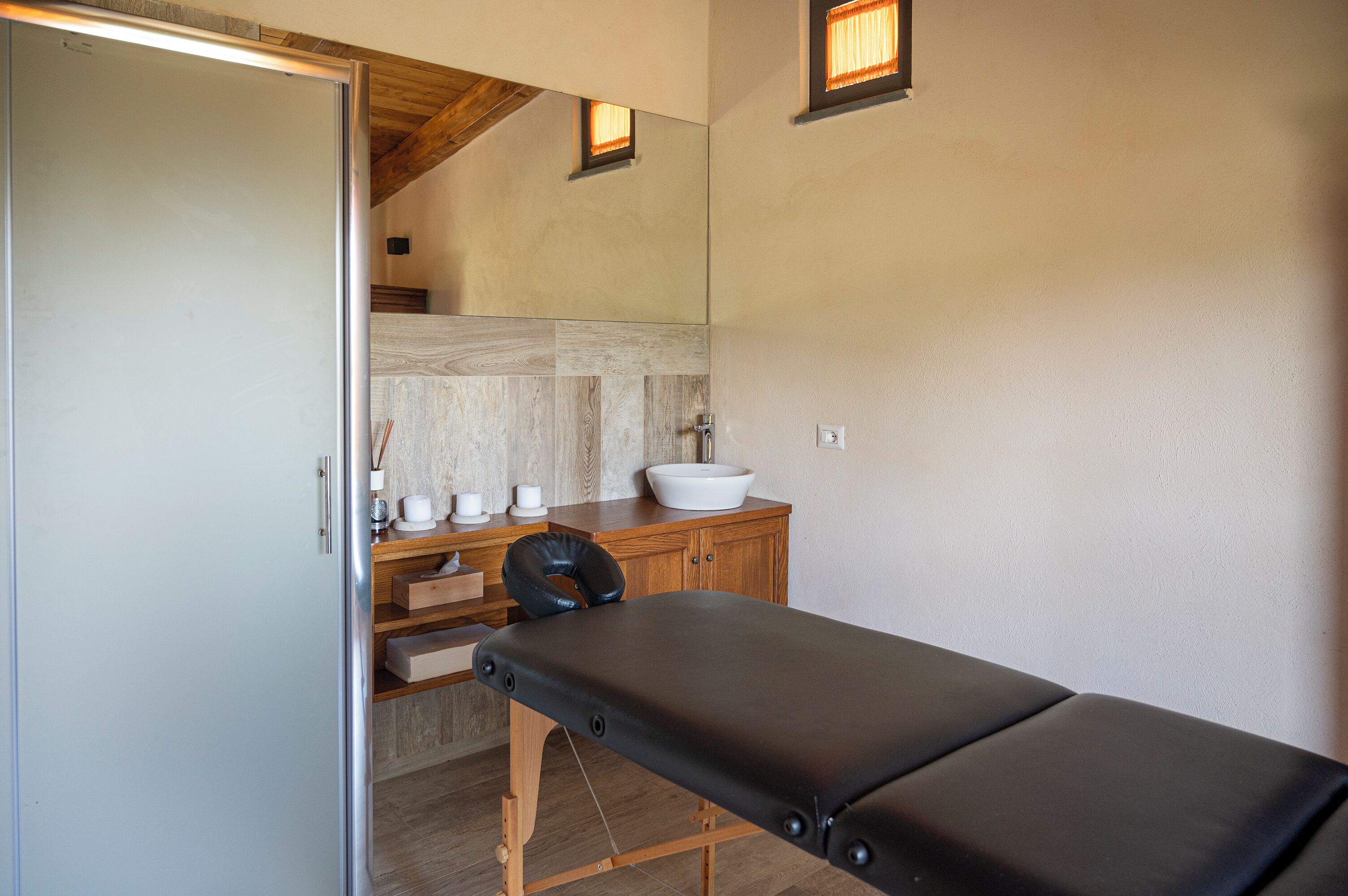 Une salle de soins équipée d’une table de massage, d’un meuble en bois et d’un lavabo.