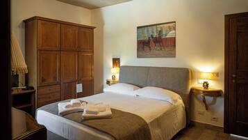 Un dormitorio ordenado con una cama grande, un armario de madera, lámparas de noche y un cuadro de caballos.