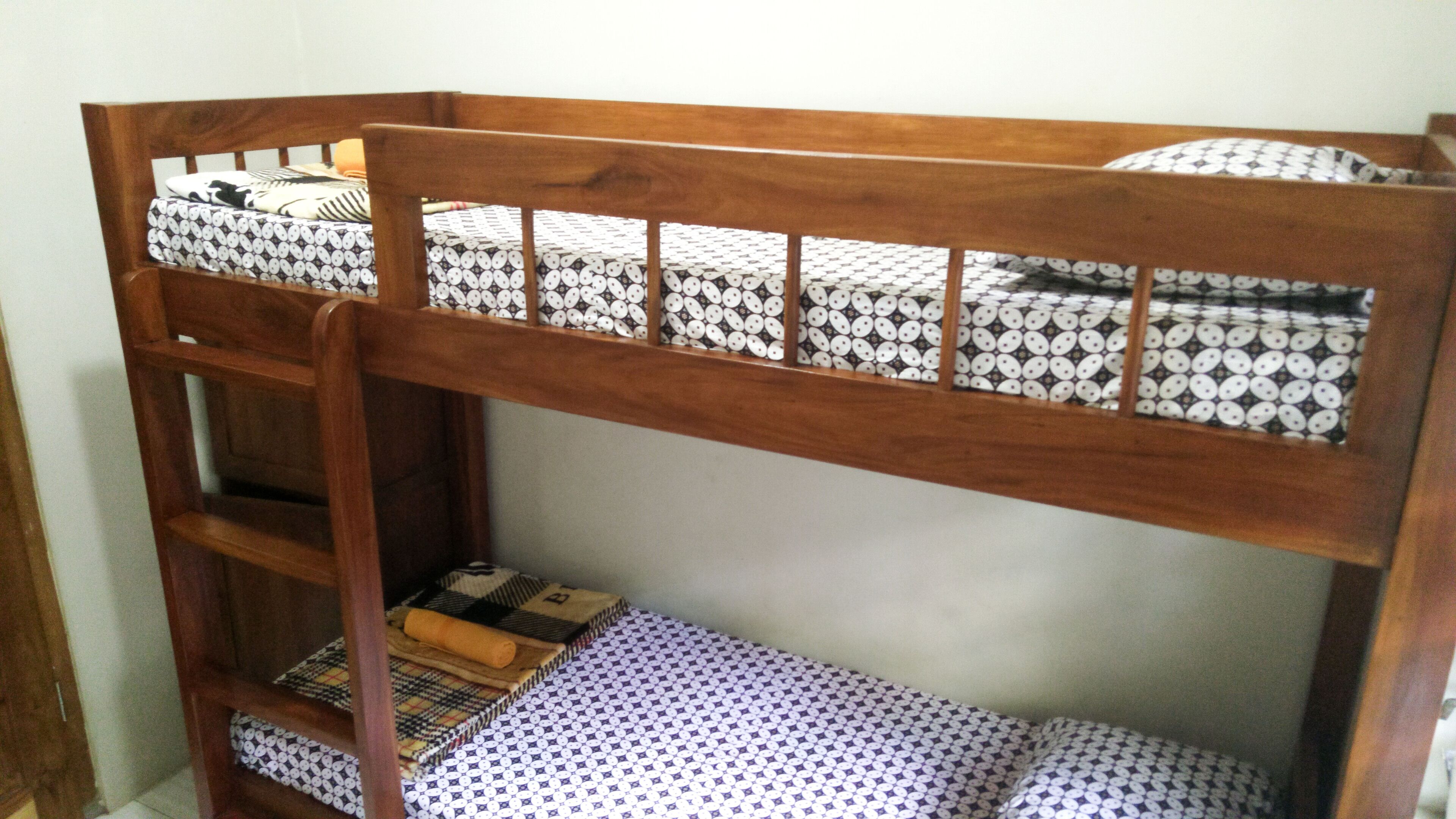 A bunk bed with patterned bedding and a wooden ladder.