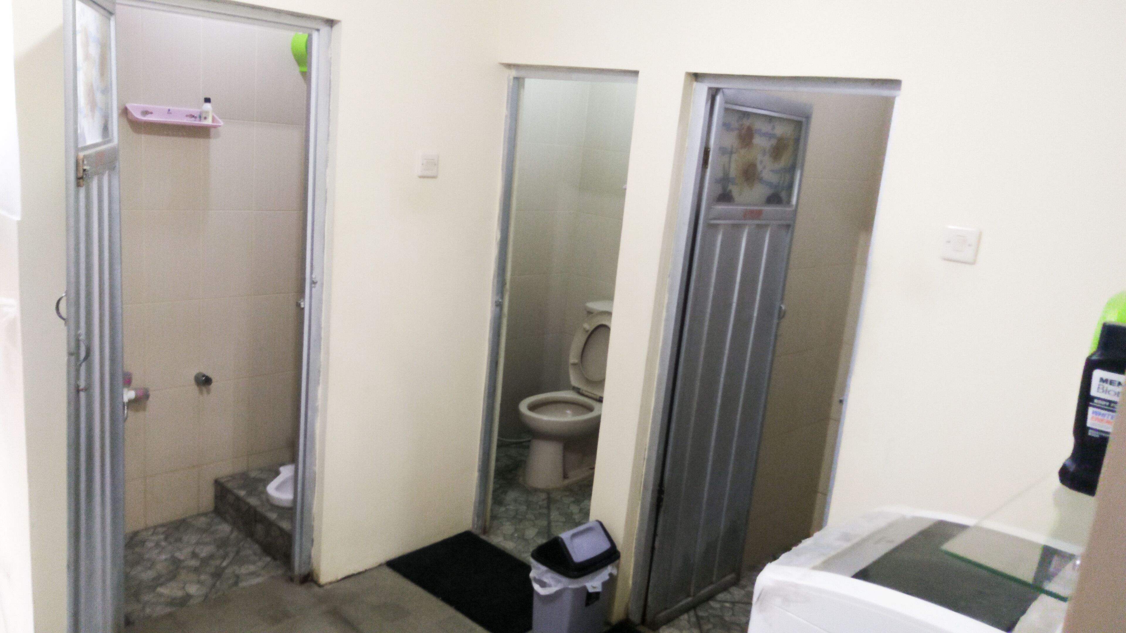 A small bathroom with a toilet, a shower stall, and a trash bin.