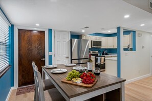Enjoy meals in this well-equipped kitchen with a central island, stainless steel appliances, and a dining table set for a meal.