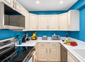 A modern kitchen with white cabinets, a black stove, and a blue accent wall.