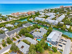 Zona residencial costera con varios edificios, un puerto deportivo y una vista despejada del océano.