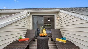 Ein Balkon mit zwei Lounge-Sesseln, einem Korbstuhl-Tisch und einer Obstschale.