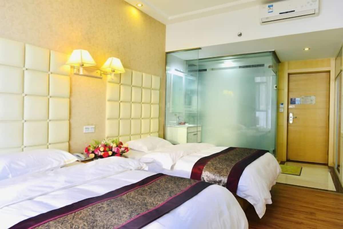 A hotel room with two beds, a glass elevator, and a wooden door.