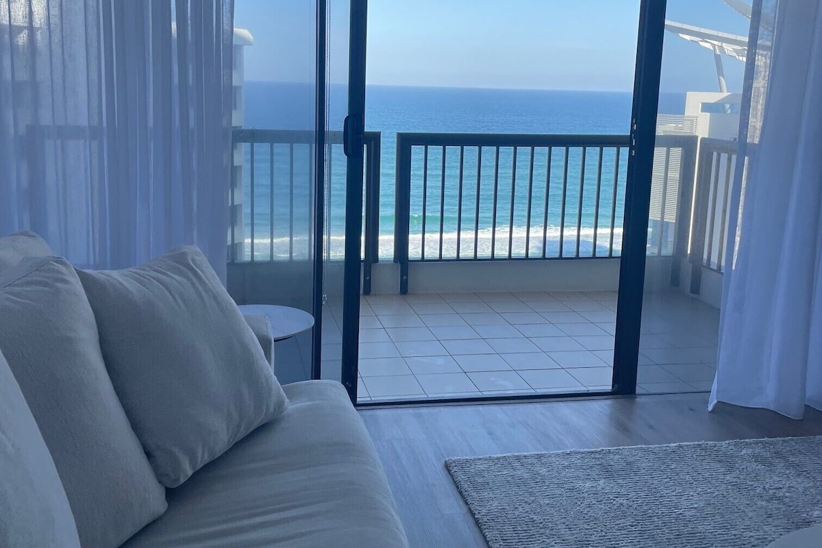 Uma varanda com vista para o mar, um sofá e uma mesa pequena.