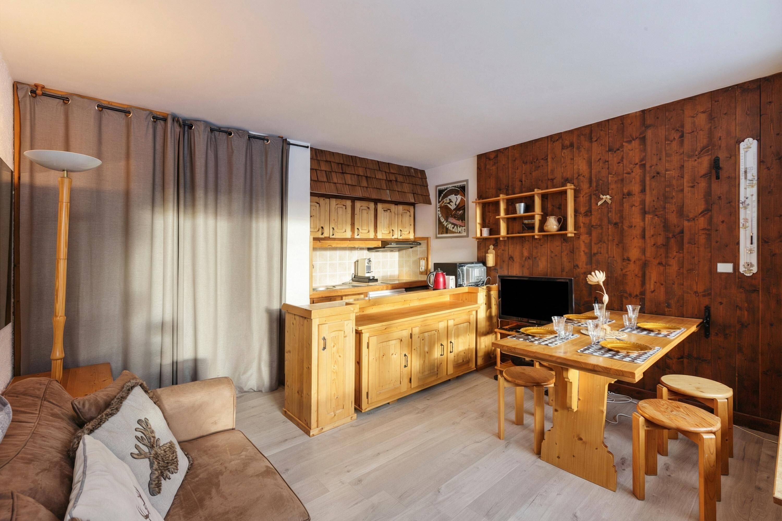 Ein gemütliches Wohnzimmer mit einem braunen Sofa und einem Holzesstisch, gedeckt für vier Personen.